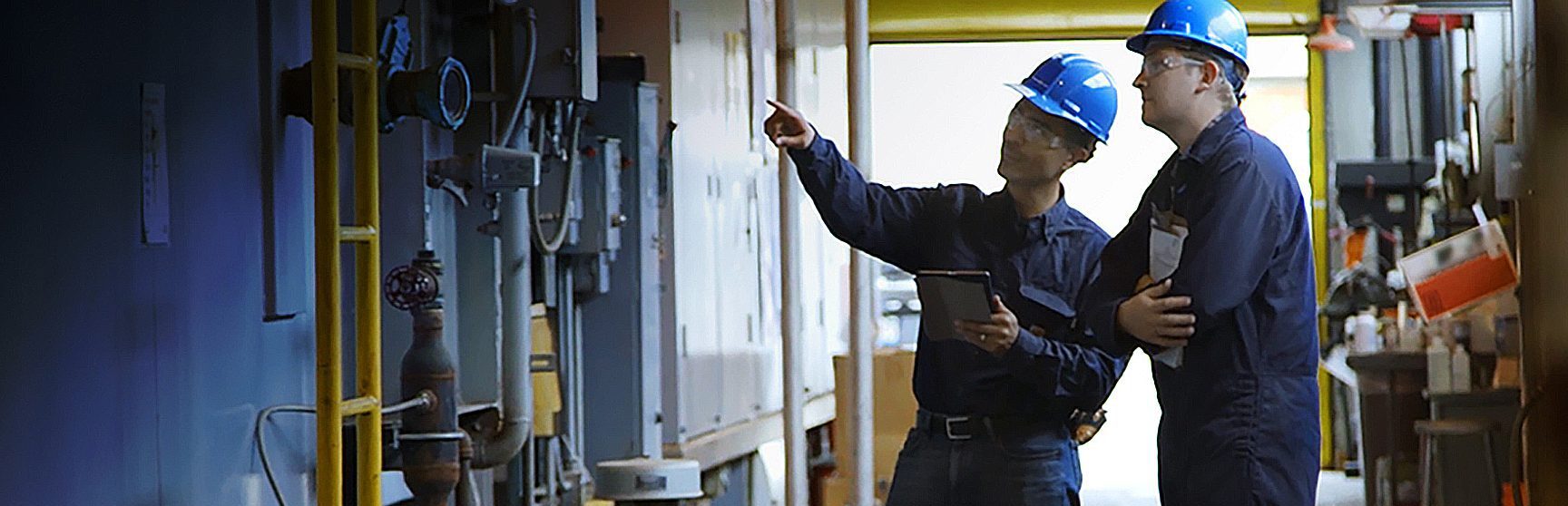 Two people with hard hats and clipboards walking around a power plant