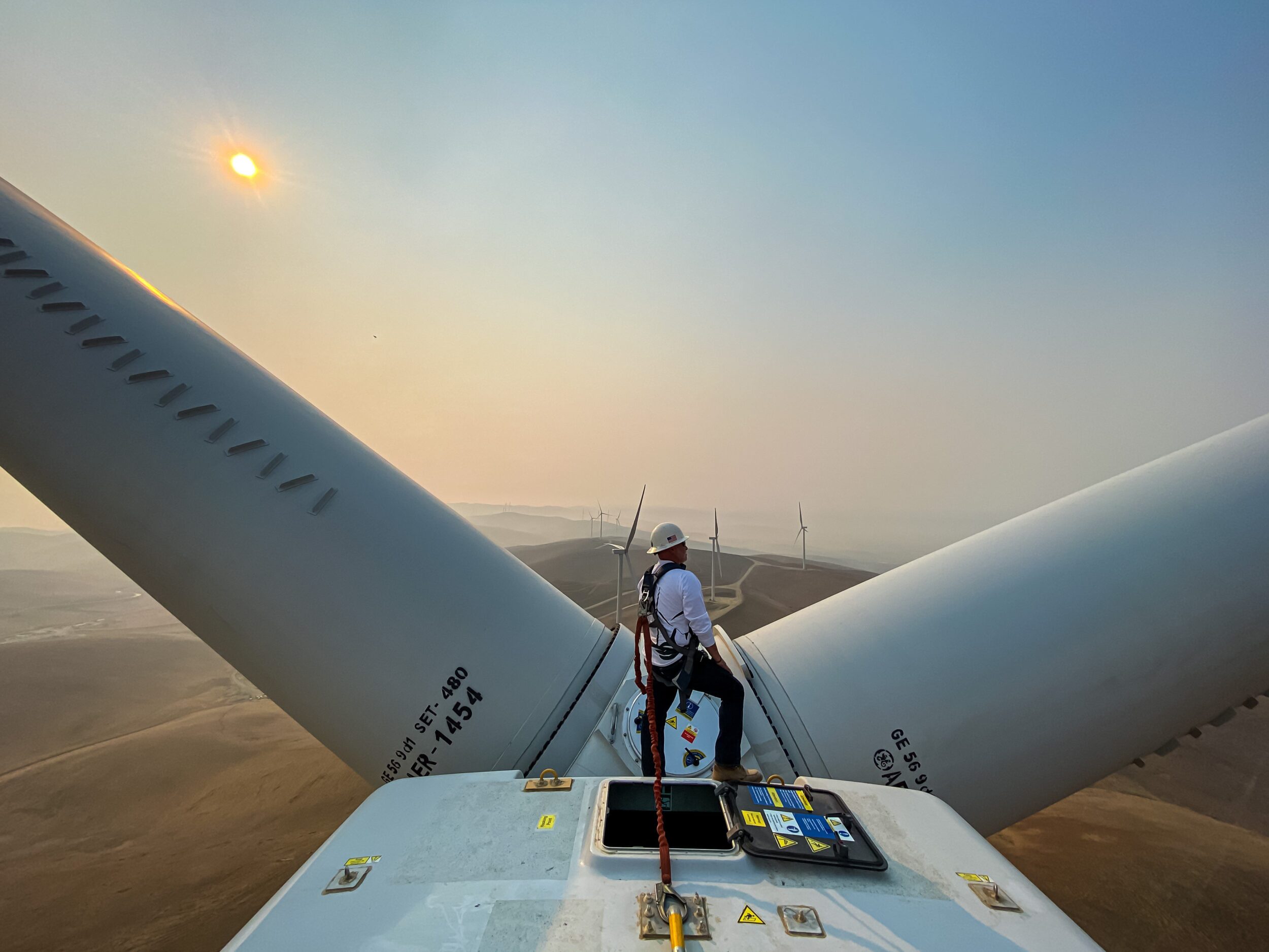 Man looking out on the horizon on top of wind turbine in California.