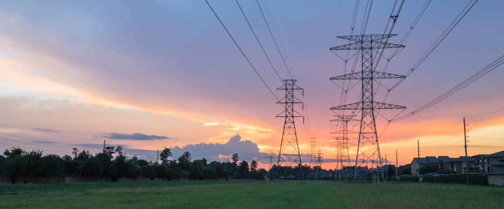 Group silhouette of transmission towers (power tower, electricity pylon, steel lattice tower) at twilight in US. Texture high voltage pillar, overhead power line, industrial background. Panorama style