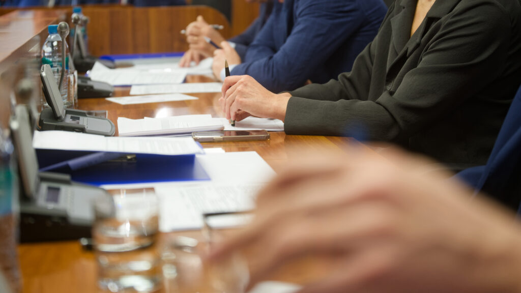 close up of peoples hands and paper in a board meeting